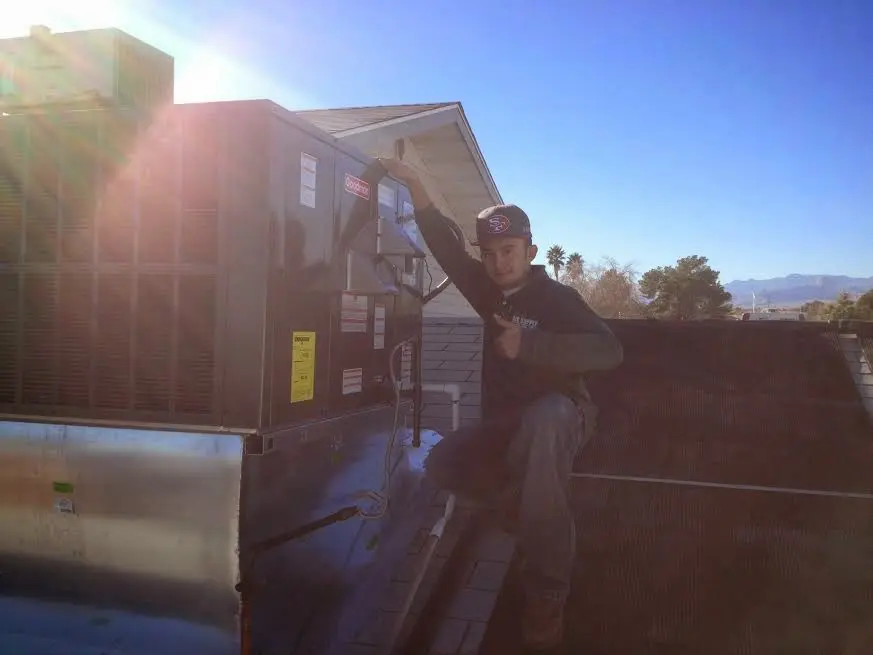 HVAC technician performing Air Duct Cleaning on a rooftop unit in Belmont